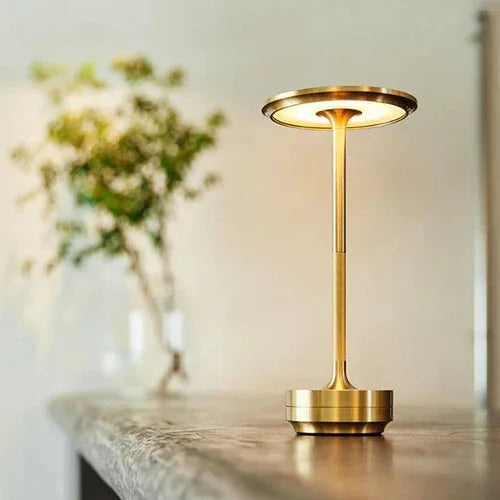 Gold Evora portable table lamp beside a vase of flowers